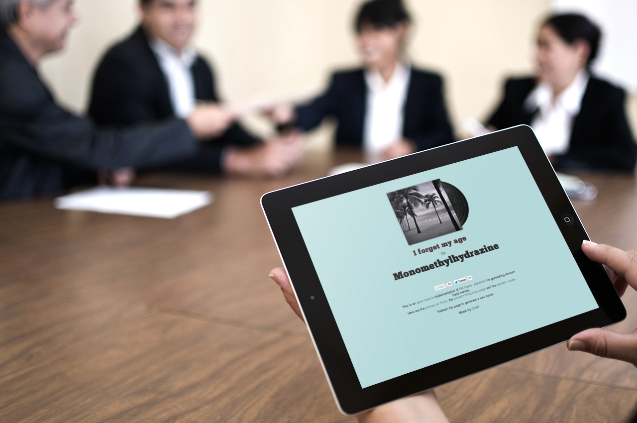 Hands holding an iPad that displays a made-up album: I forget my age by Monomethylhydrazine. In the background is a serious business meeting with four people in suits.